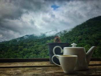 Coffee cup on table against mountains