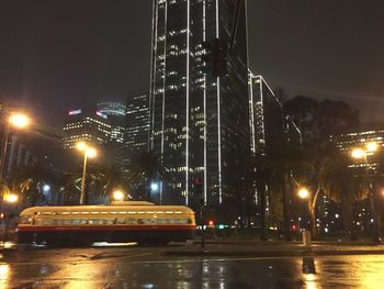 Illuminated road in city against sky at night