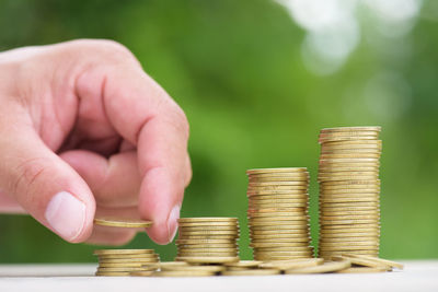 Close-up of hand holding stacking coins on table