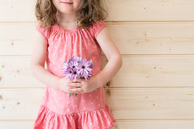 Close-up of girl standing against wooden wall