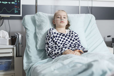 Girl with oxygen tube lying on bed at hospital