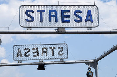 Low angle view of signs on metallic structure against sky