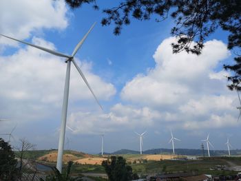 Wind turbines on field against sky