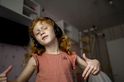 Girl with headphones listening to music and gesturing at home