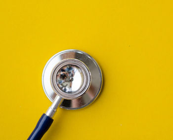 Directly above shot of stethoscope over yellow background