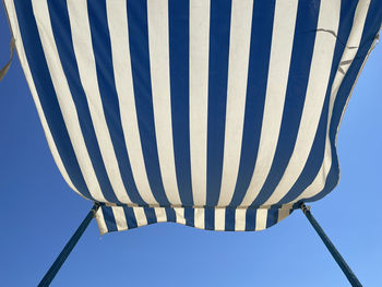Blue and white striped sunshade against blue sky