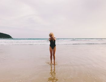 Full length of woman standing at beach against sky