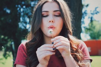 Close-up of young woman blowing dandelion