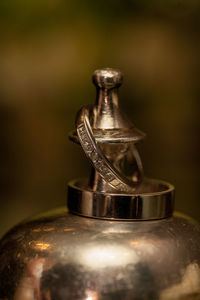 Wedding rings detail on metal chalice with bridal bouquet in the background