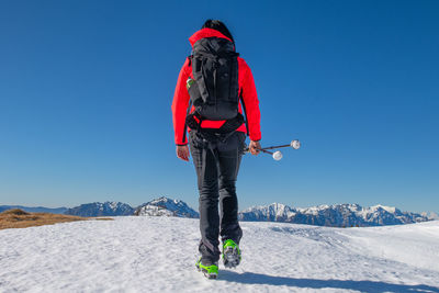 Rear view of woman on snowcapped mountain against clear sky