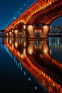 Illuminated bridge over river at night