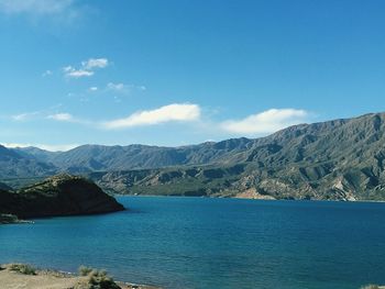 Scenic view of sea and mountains against blue sky