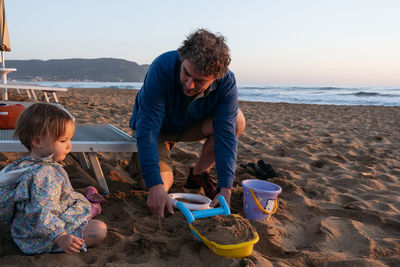 Father and child sitting at the beach in the sunset