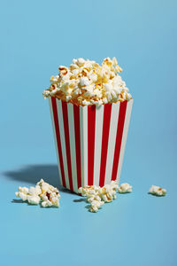 Popcorn in red striped container over blue background