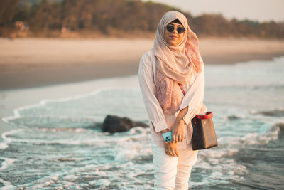 Portrait of young woman standing at beach