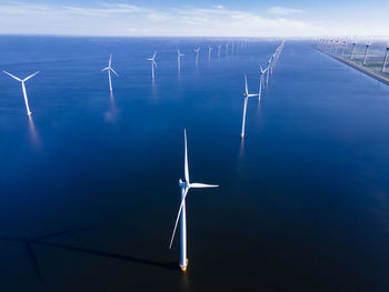 Wind turbine in water against sky