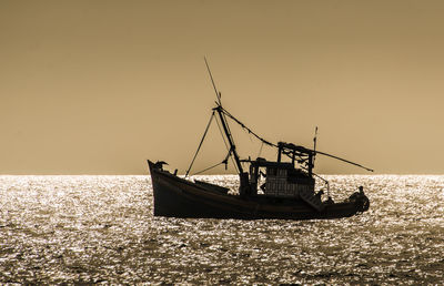 Sailboat sailing in sea against clear sky during sunset