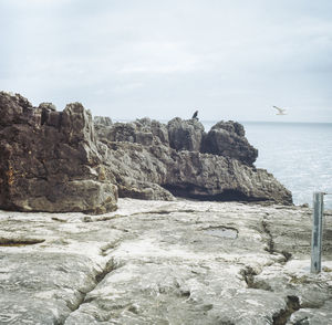 Scenic view of rocks by sea against sky