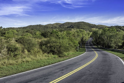 Road amidst green landscape against sky