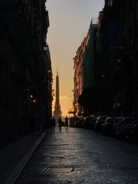People walking on street amidst buildings during sunset