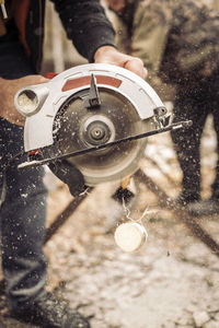 Hands of man cutting wood log with circular saw