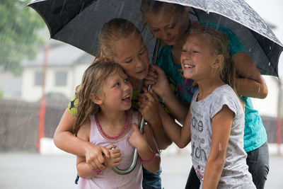 Friends with umbrella enjoying in rain