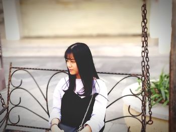 Young woman looking away while sitting on swing