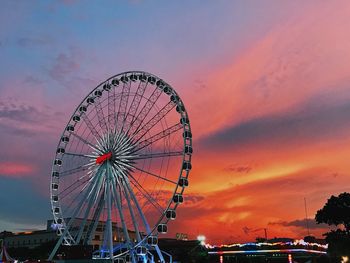 Low angle view of ferris wheel against sky at sunset