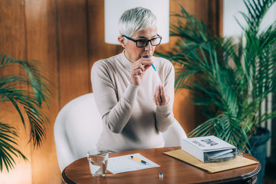 Midsection of woman using smart phone while sitting on table