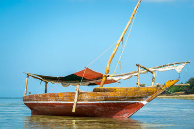 Fishing boat in sea against clear blue sky