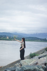 Woman standing on rock against sky