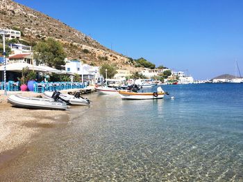 Boats moored at harbor against clear blue sky