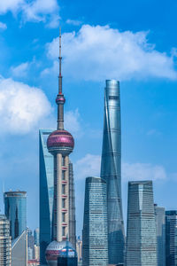 Low angle view of buildings in city against cloudy sky