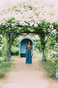 Woman standing by railing against plants