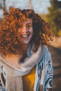 Smiling young woman standing against trees during sunny day