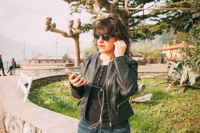 Woman using mobile phone while standing at park