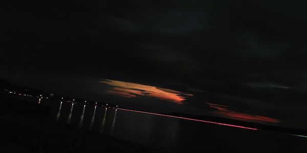 Silhouette illuminated lights against sky at night