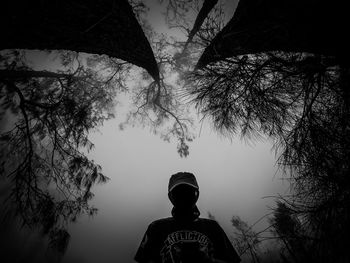 Low angle view of silhouette man standing by tree against sky