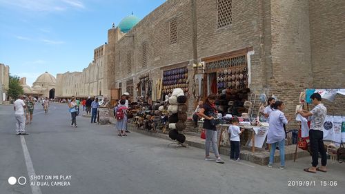 People on street against buildings in city