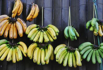 Bananas hanging against fence for sale at market