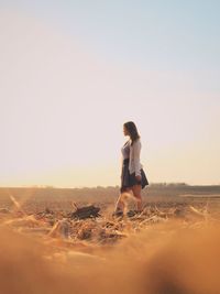 Beautiful woman walking on agricultural field against sky