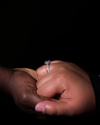 Close-up of man holding hands over black background