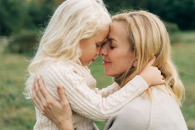 A close hug between a little daughter and a middle-aged mom.