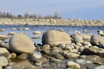 Close-up of pebbles on beach against sky