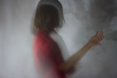 Side view of woman standing against wall