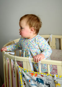 Cute girl of ten months old, playing alone in a crib at home in the afternoon or in the morning.