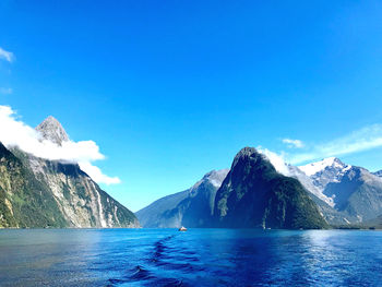 Scenic view of sea and snowcapped mountains against blue sky