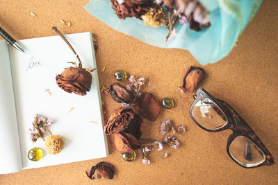 Directly above shot of books and eyeglasses with dry roses on table