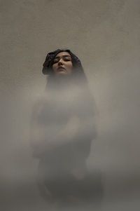 Portrait of woman standing against wall