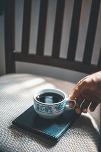 Cropped hand of person holding coffee cup on diary